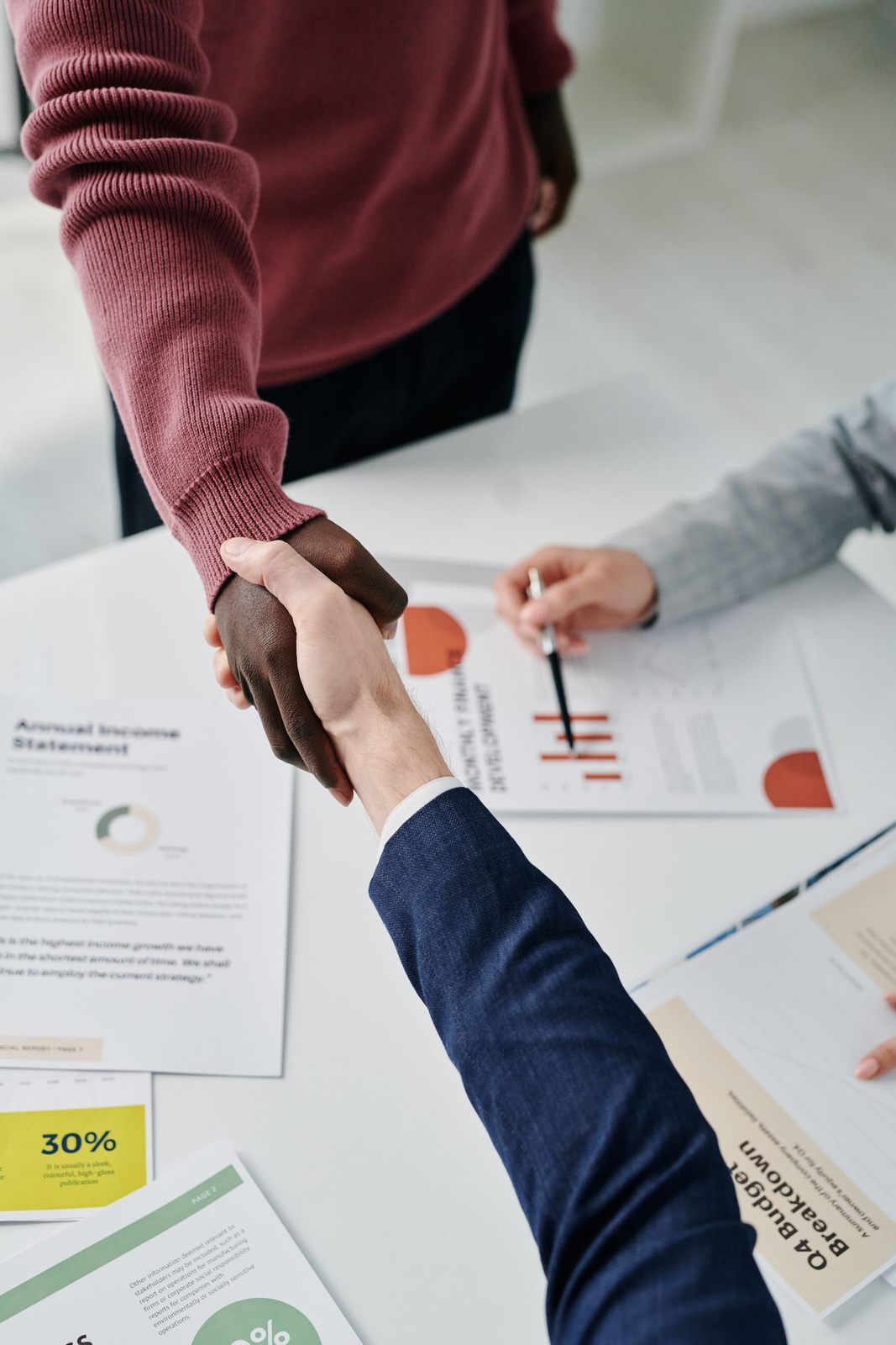 Professional handshake over financial documents symbolizes successful business partnership and teamwork