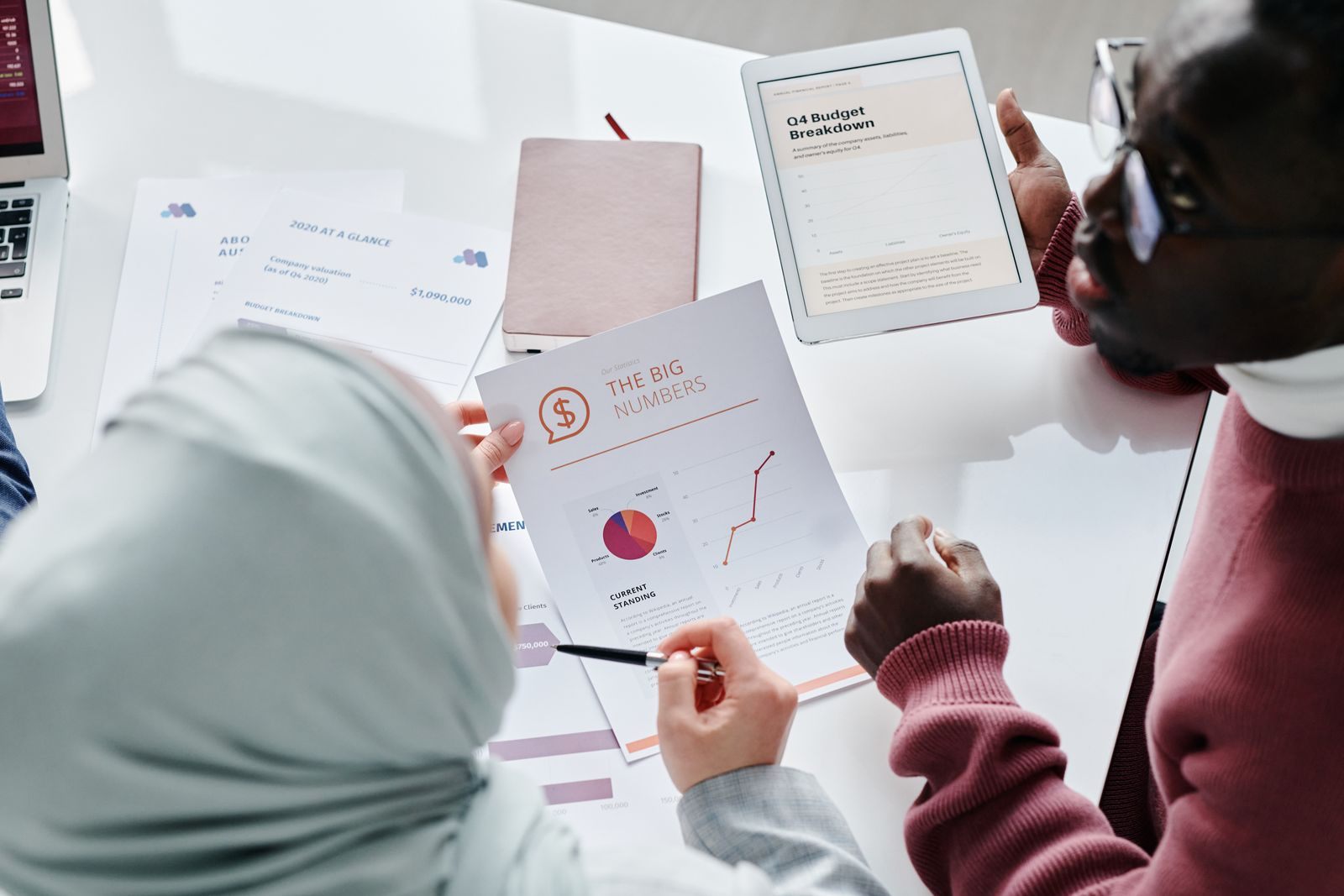 Two colleagues reviewing financial documents and graphs during an office meeting